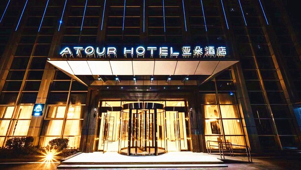L’extérieur de l’hôtel Atour, avec son enseigne lumineuse et son entrée dotée d’une porte tournante.