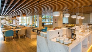 Un restaurant moderne avec des poutres en bois au plafond, des chaises bleues et un comptoir en marbre où l’on trouve tout le nécessaire pour le service.