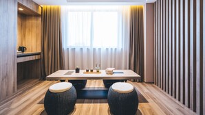 A modern room with a wooden floor, a long table with stools, a window with curtains, and a wooden panel wall. - Atour Hotel Hongen Road Forest Park Chongqing (Chongqing)