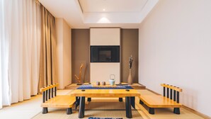 A modern dining area with a wooden table and benches, a flat-screen TV mounted on the wall, and a vase with dried branches on a side table. - Atour Hotel Hongen Road Forest Park Chongqing (Chongqing)