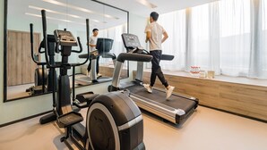 A modern home gym with a treadmill, elliptical, and stationary bike, large mirror, and large windows with curtains. - Atour Hotel Hongen Road Forest Park Chongqing (Chongqing)