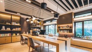 A modern office space with a long wooden desk, multiple chairs, and bookshelves filled with books. - Atour Hotel Nanbin Road Chongqing (Chongqing)