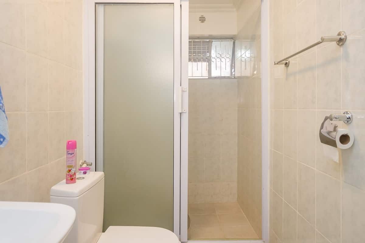 A bathroom with a toilet, a shower, and a sink.