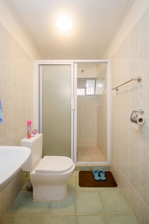 A bathroom with a toilet, a shower, and a sink. - Esterina Suites (Nairobi)