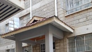 A multi-story building with a covered entrance, a staircase with metal railings, and a tiled ground floor. - Esterina Suites (Nairobi)