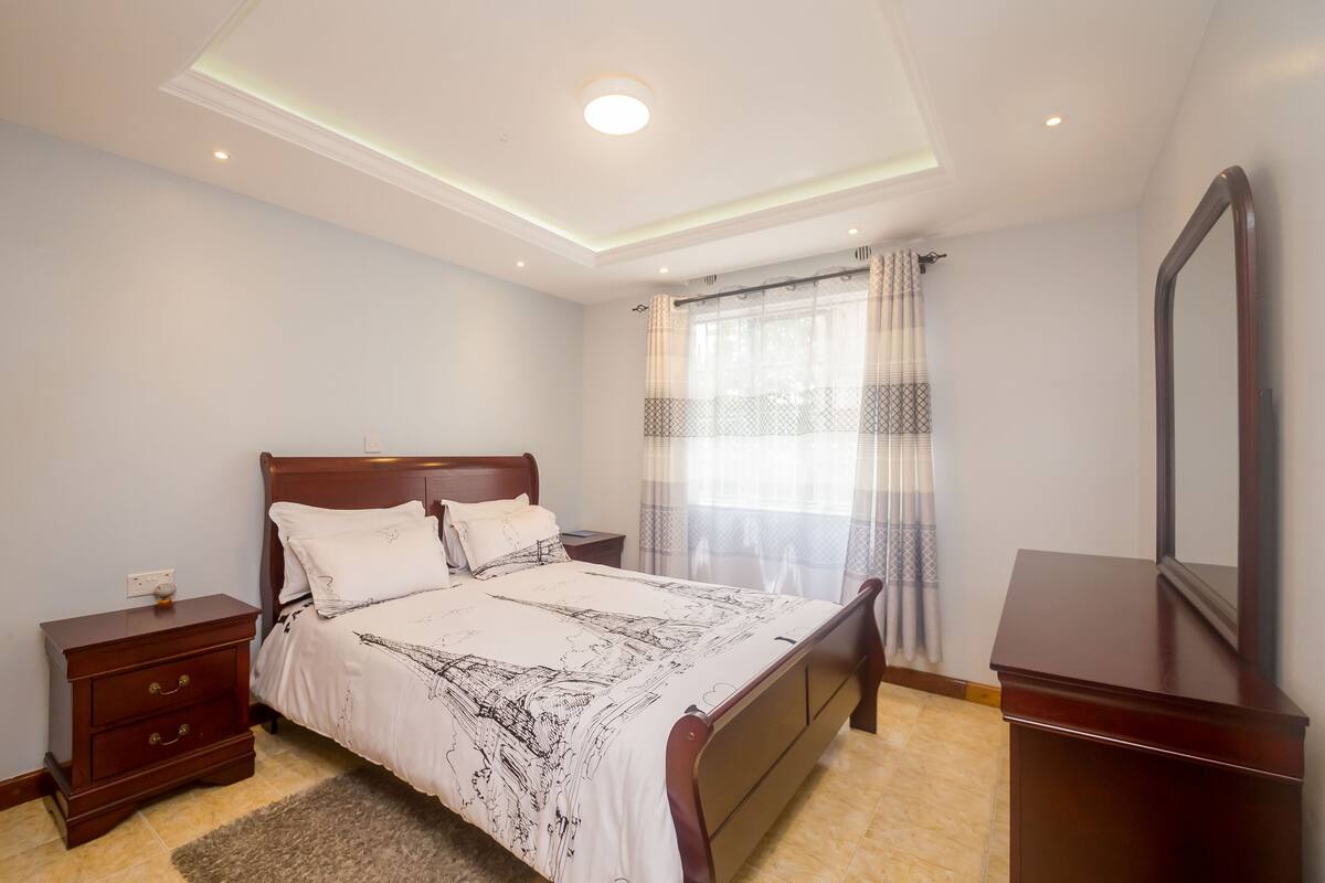 A bedroom with a bed, nightstands, a dresser, and a mirror.
