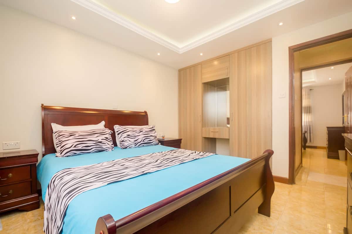 A bedroom with a bed, wooden headboard, and a wardrobe.