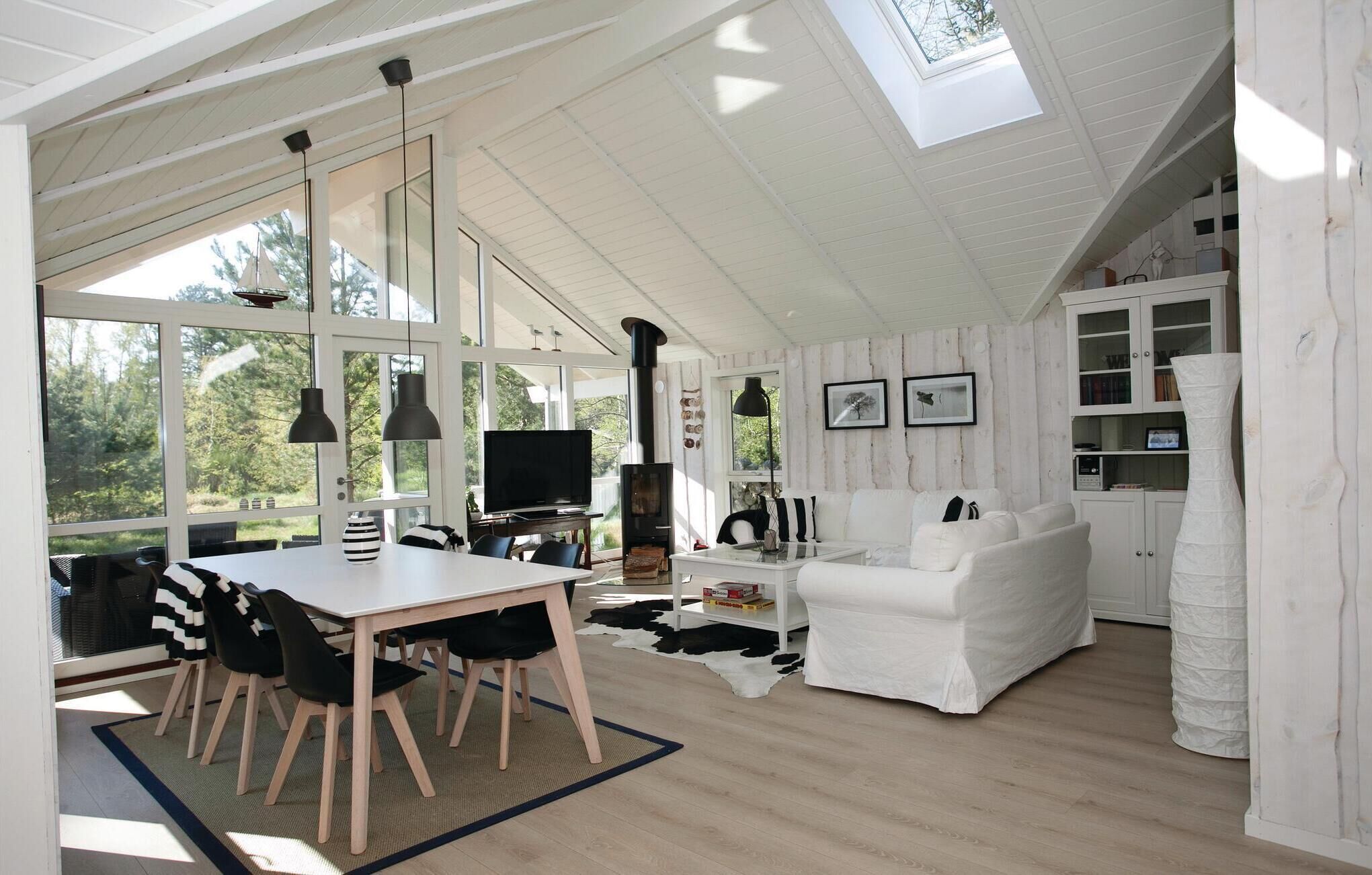 A spacious living area with a high ceiling, large windows, a fireplace, and a cozy seating arrangement.