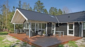 A modern beach house with a wooden deck, outdoor seating, and large windows. - Amazing home in Højby with sauna (Højby)