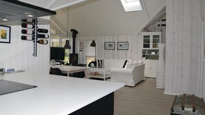A modern kitchen with a central island, a dining area with a white table and chairs, a white sofa, and a built-in bookshelf. - Amazing home in Højby with sauna (Højby)