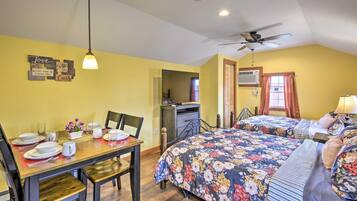 A bedroom with two beds, a dining table, and a ceiling fan.