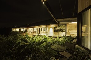 A modern building with a covered outdoor area featuring a dining table and chairs, surrounded by lush greenery. - Hotel Casa Du Velo (Filandia)