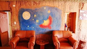 Una habitación con dos sillones de cuero, una mesita de madera y un mural de un pájaro volando bajo un cielo estrellado con una luna.