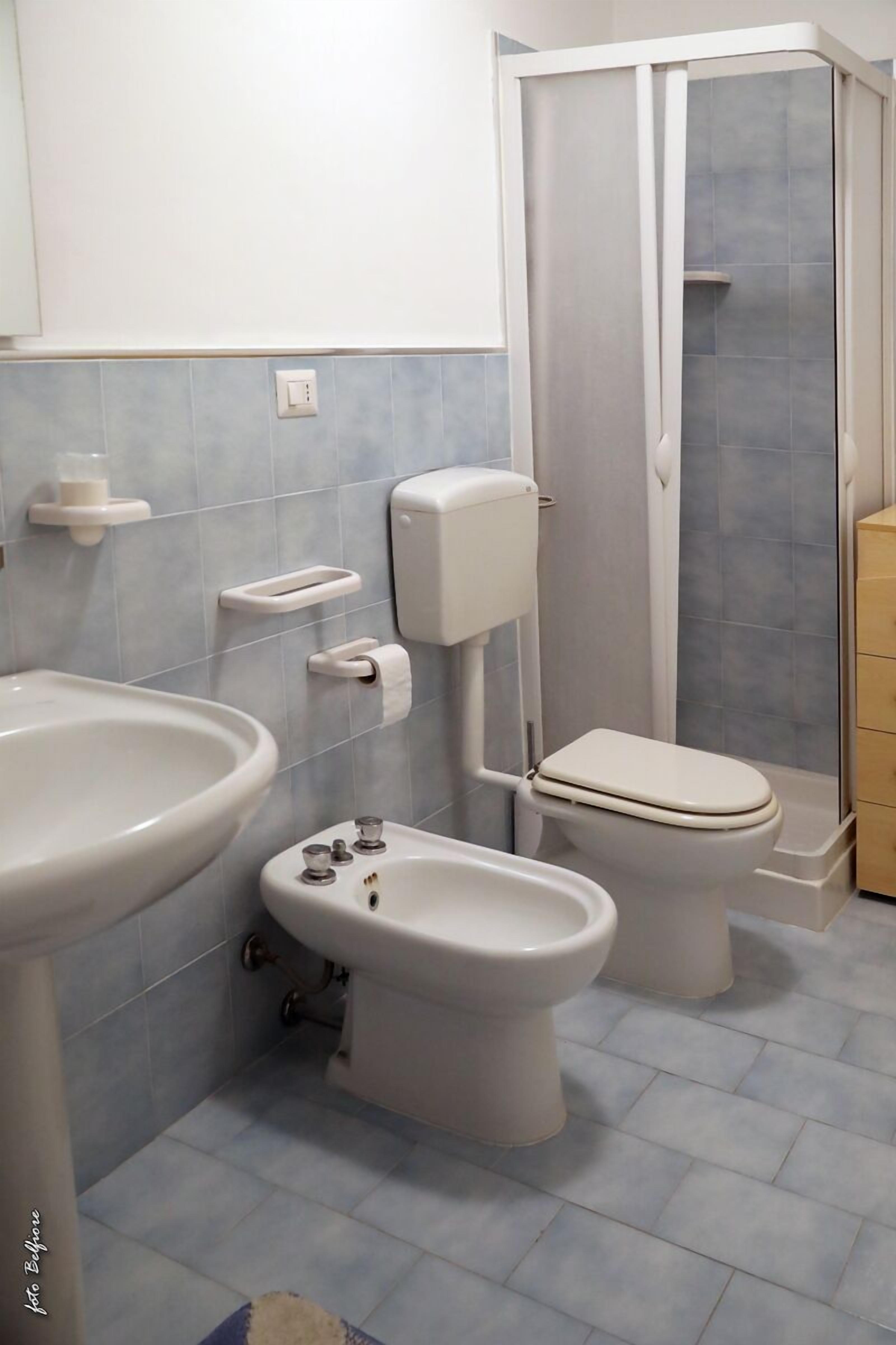 Et badeværelse med håndvask, bidet, toilet og bruser.