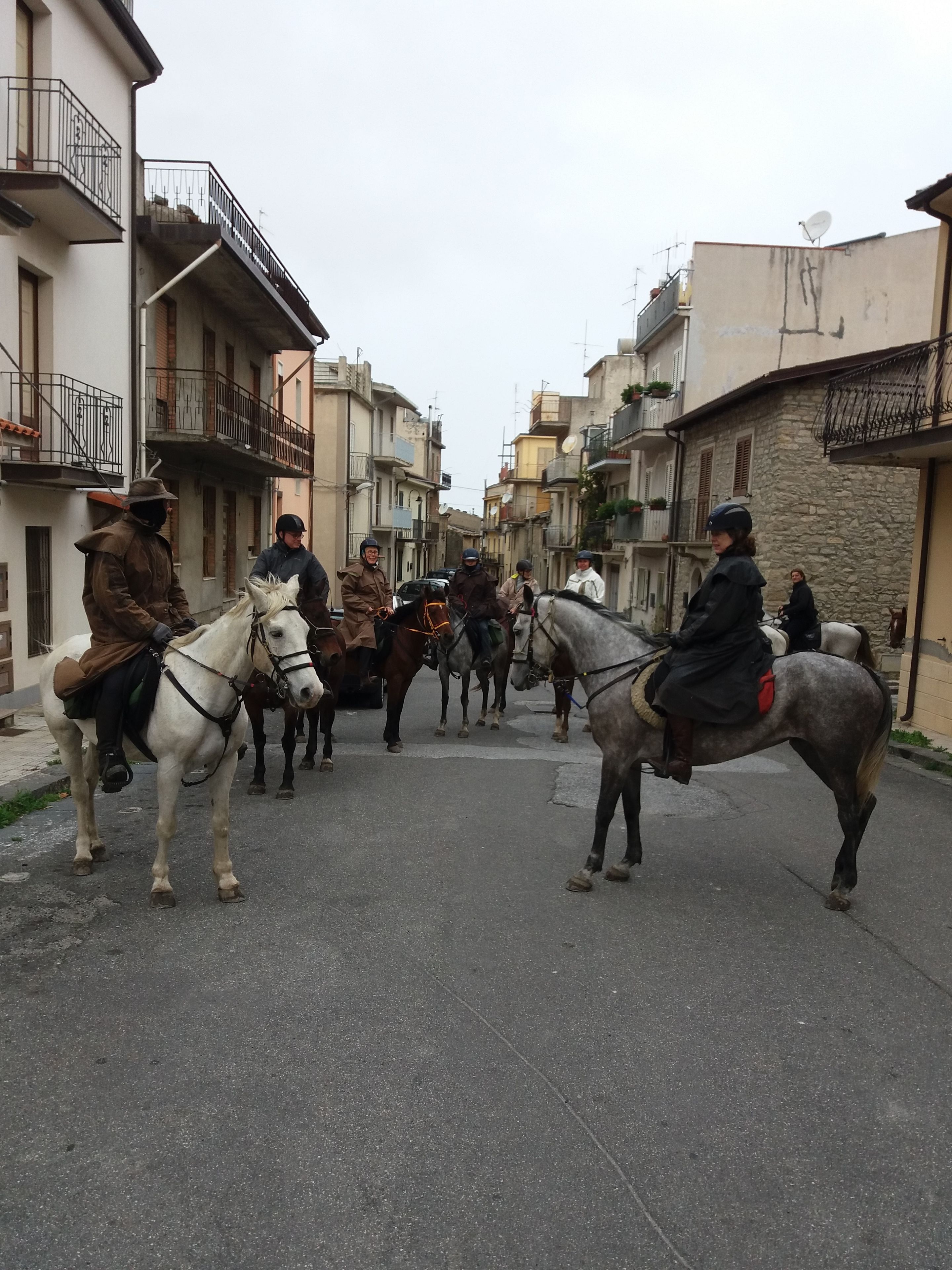 A street scene with people riding horses.