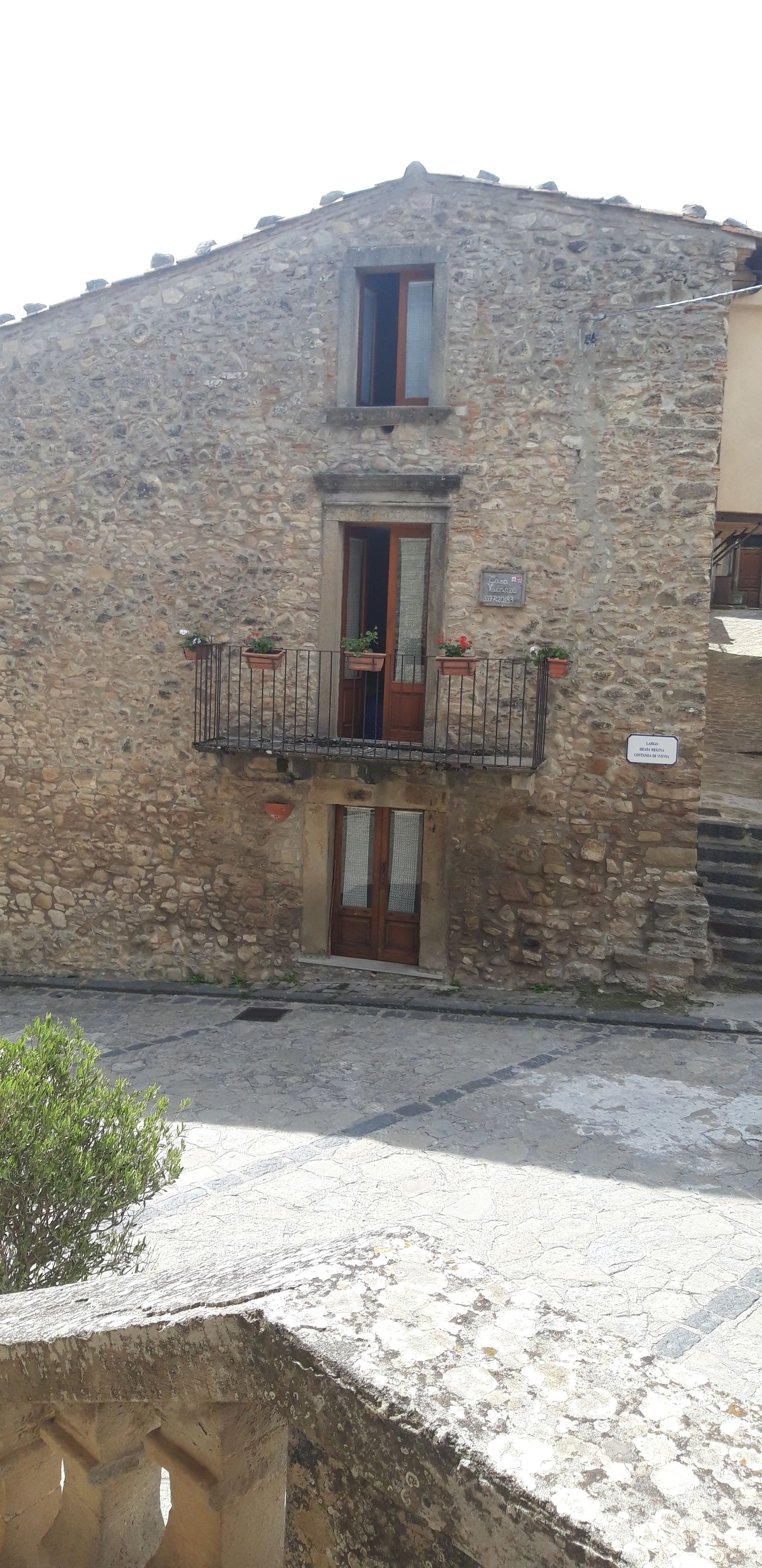 A stone building with a balcony, a door, and a small window.