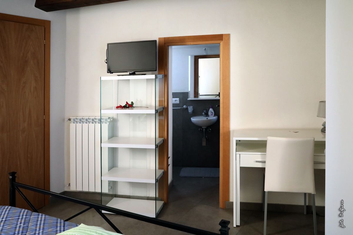 Une chambre comprenant un lit, un bureau, une chaise, une télévision, une armoire et une salle de bain.