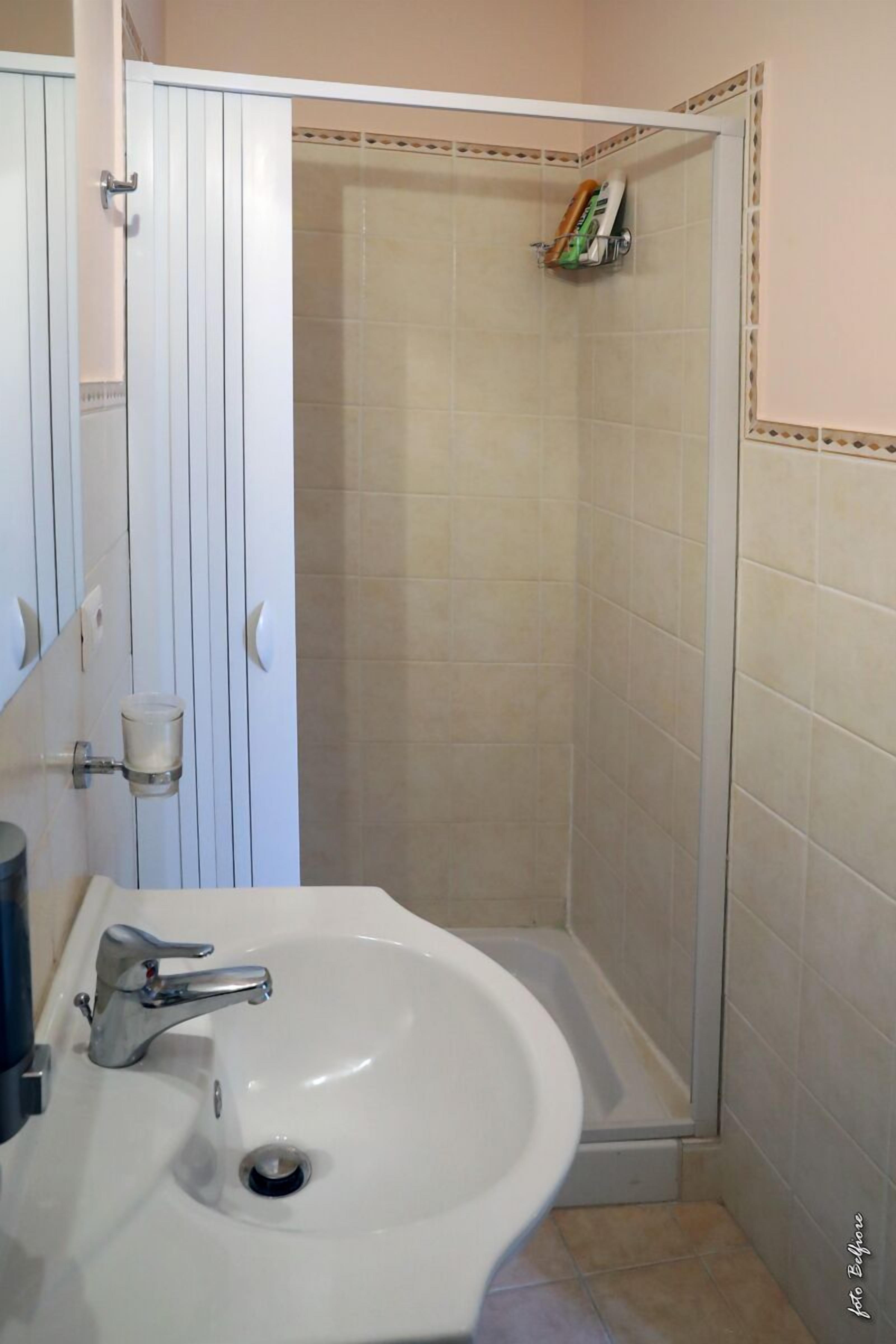 Une salle de bain avec un lavabo blanc, un miroir et un espace douche.
