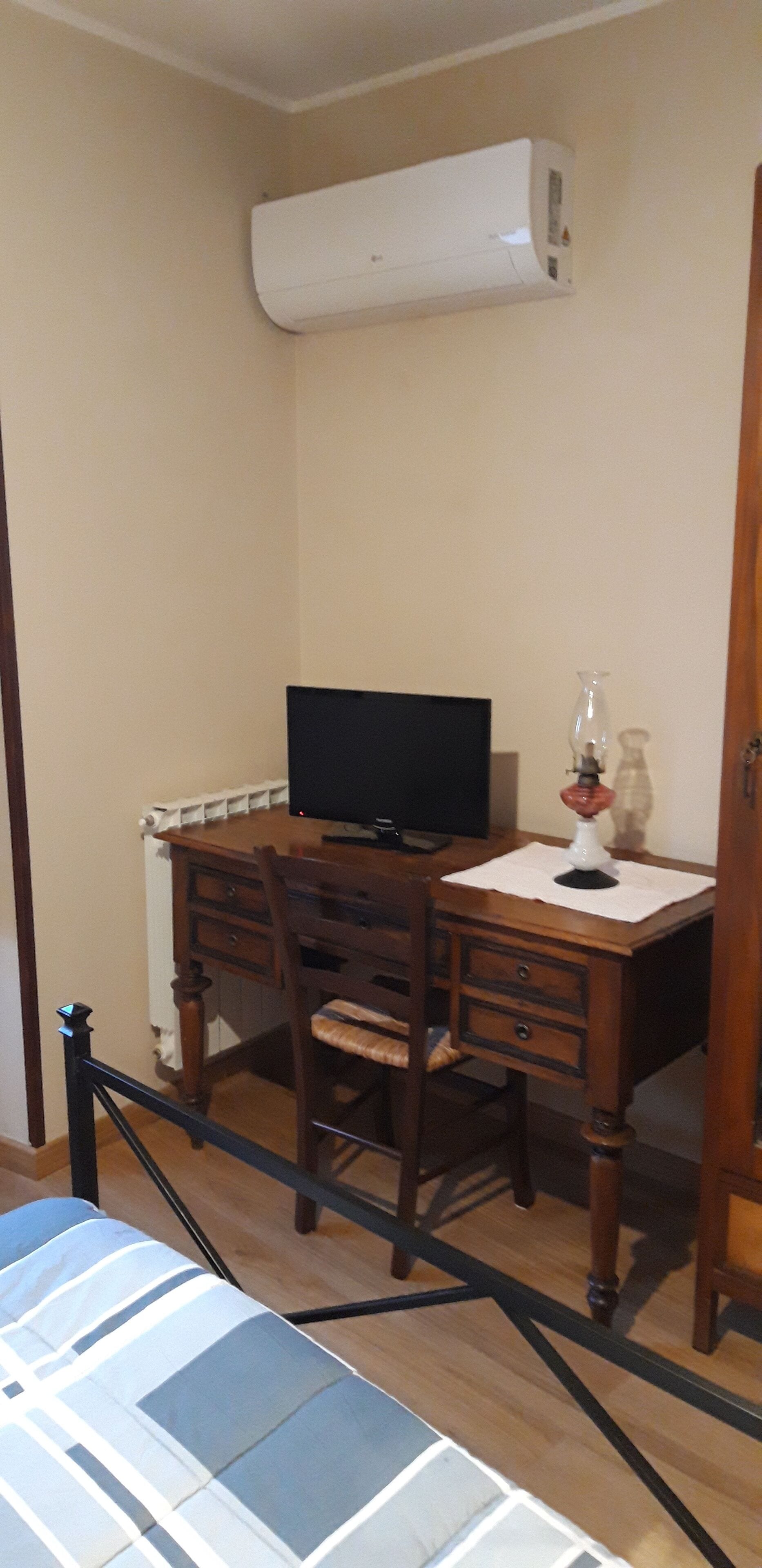 Ein Zimmer mit einem Holztisch, einem Stuhl, einem Fernseher und einer Wand-Klimaanlage.