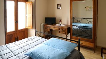 A bedroom with a bed, a desk, a chair, a wardrobe, and a television.