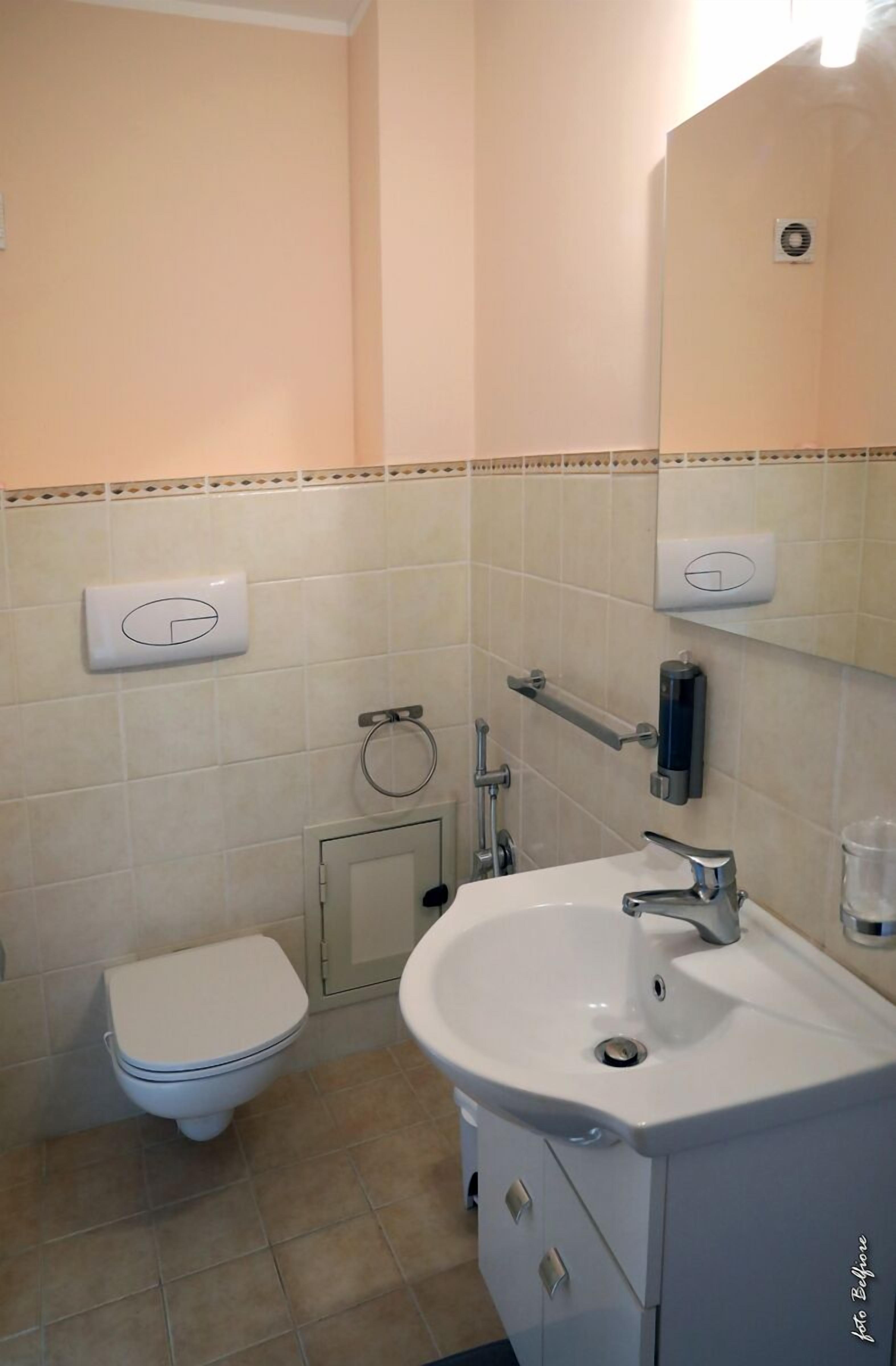 Une salle de bain équipée de toilettes, d’un lavabo et d’un distributeur de serviettes.