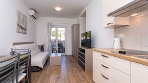 A modern, well-lit room with a bed, a dining table, a TV, and a kitchenette. - Holiday apartment mit Klimaanlage und Terrasse (Baška)