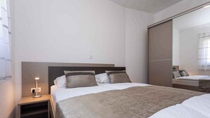 A bedroom with a bed, bedside table, lamp, and a large mirror. - Holiday apartment mit Klimaanlage und Terrasse (Baška)