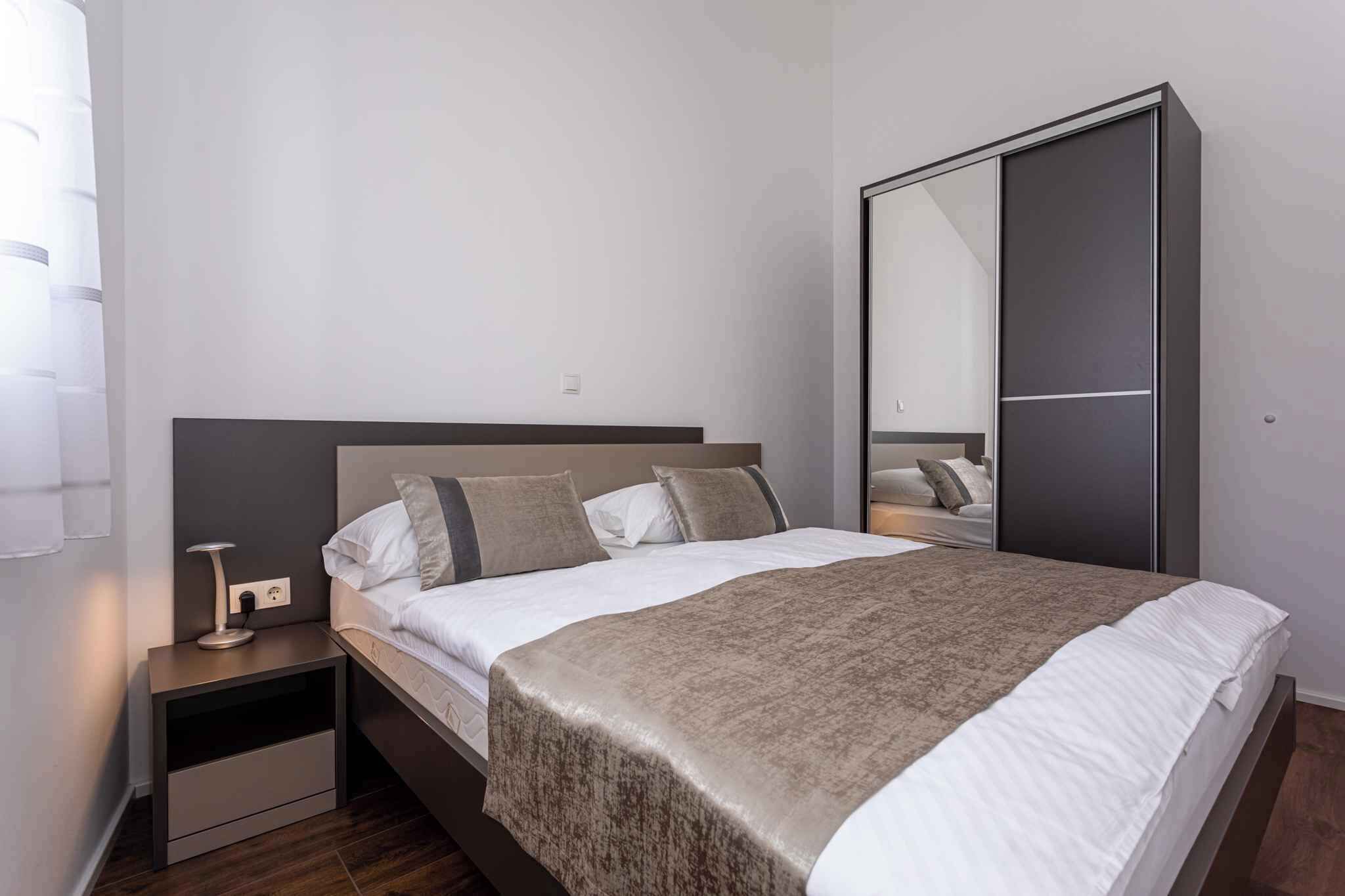 A modern bedroom with a bed, bedside table, and a wardrobe.