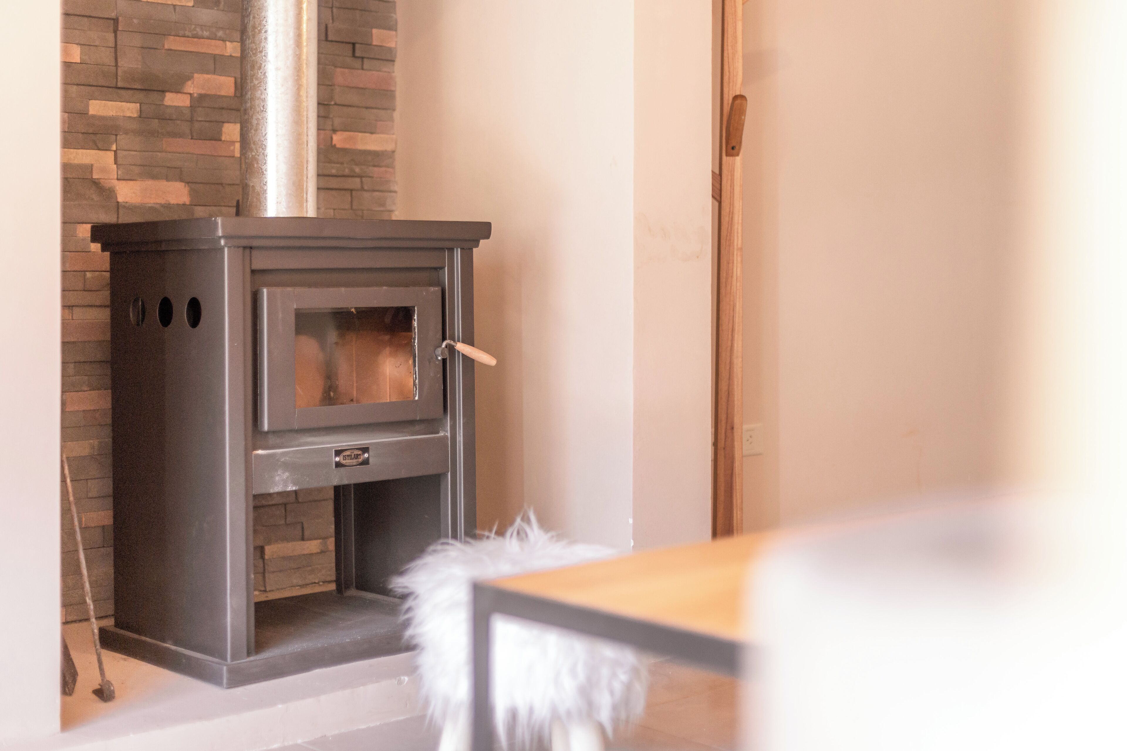 A modern fireplace with a glass door, a metal exterior, and a stone accent wall.