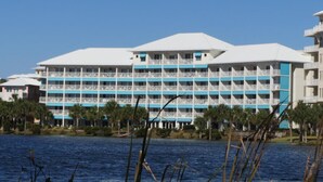 Un hotel de varios pisos con balcones, situado cerca de una masa de agua.