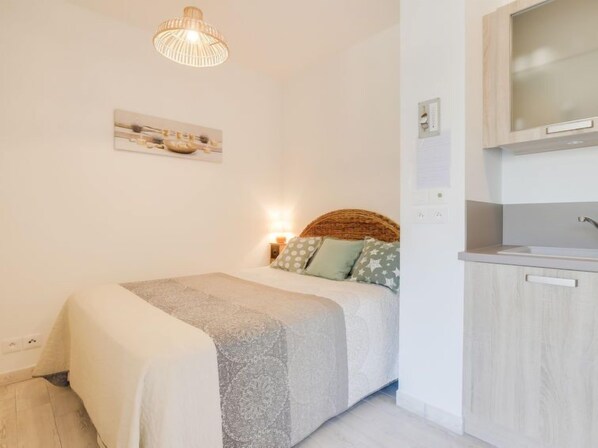 A bedroom with a bed, bedside lamp, and a small wall-mounted shelf. - Les Jardins d'Eyrac by Interhome (Arcachon)