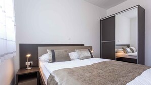 Een moderne slaapkamer met een bed, bedlampje en een grote spiegel.