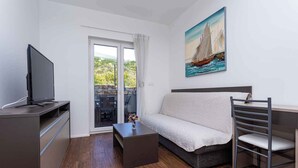 Een moderne woonkamer met een bank, een televisie op een kast, een salontafel en een schilderij van een zeilboot.