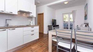 Een moderne keuken met witte kasten, een houten aanrecht en een eethoek met een glazen tafel en metalen stoelen.