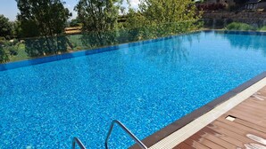 Ein klares, blaues Schwimmbecken mit Holzterrasse und Metallgeländern.