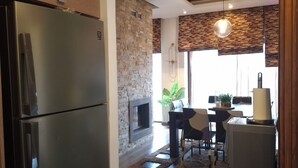 Eine moderne Küche mit integriertem Kühlschrank, einer Wand mit Steinakzenten und einem Essbereich mit Tisch und Stühlen.