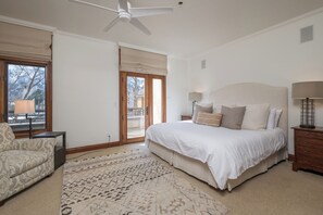 Ein Schlafzimmer mit einem großen Bett, einem Deckenventilator, einem Fenster mit Blick und einem Nachttisch mit Lampe.