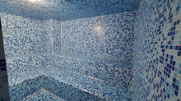A tiled room with a patterned design, a ceiling light, and a corner with a built-in bench.