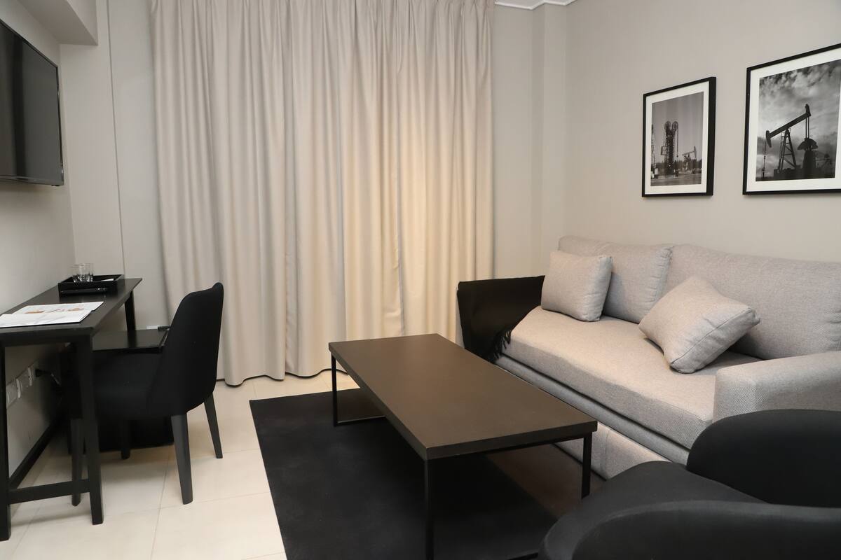 Ett modernt vardagsrum med en soffa, ett soffbord, ett skrivbord och en tv.