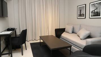 A modern living room with a sofa, a coffee table, a desk, and a TV.