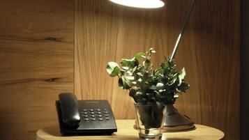 Un escritorio con una lámpara, un teléfono y un florero con plantas verdes.