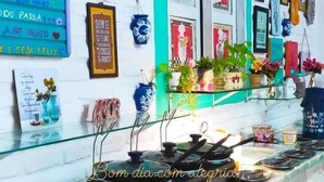 Una cafetería con fachada blanca y turquesa, decorada con varios letreros y obras de arte coloridas.