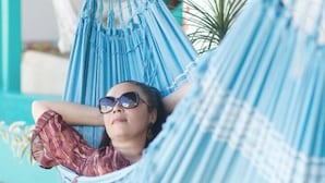 Una persona descansando en una hamaca azul al aire libre.