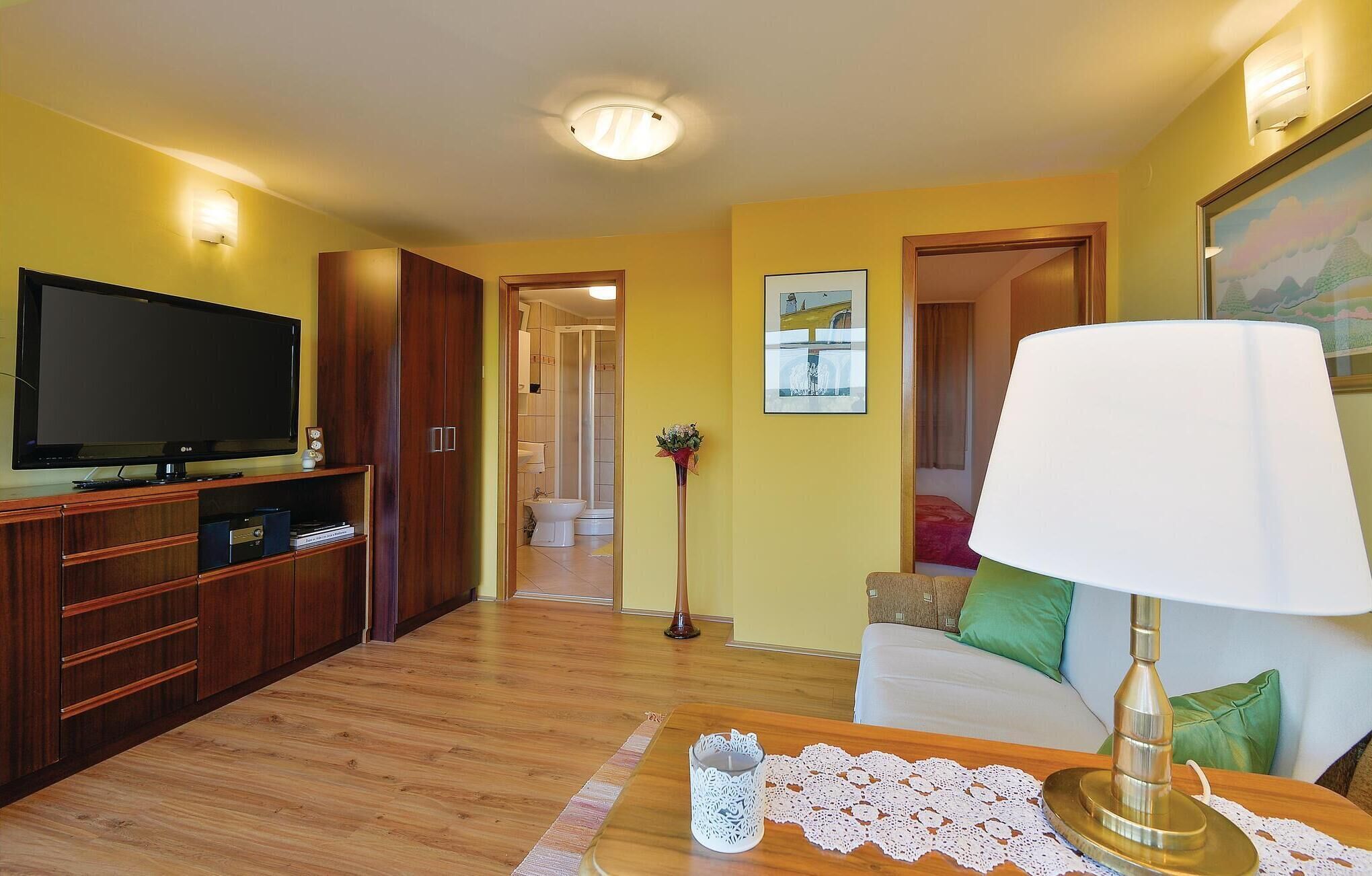 A living room with a television, wooden cabinets, a sofa, and a lamp.