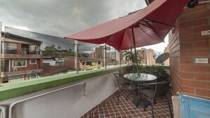 A balcony with a red umbrella, a round table, and chairs. - Ayenda 1231 Paradise Center (Medellín)