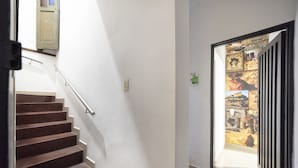 A staircase with a metal handrail, a door with a vintage design, and a wall with a framed collage of historical images. - Ayenda 1231 Paradise Center (Medellín)