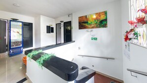 A reception area with a counter, a clock, and a wall-mounted painting. - Ayenda 1231 Paradise Center (Medellín)