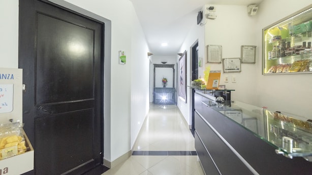 A hotel corridor with a reception desk, a black door, and a tiled floor. - Ayenda 1231 Paradise Center (Medellín)