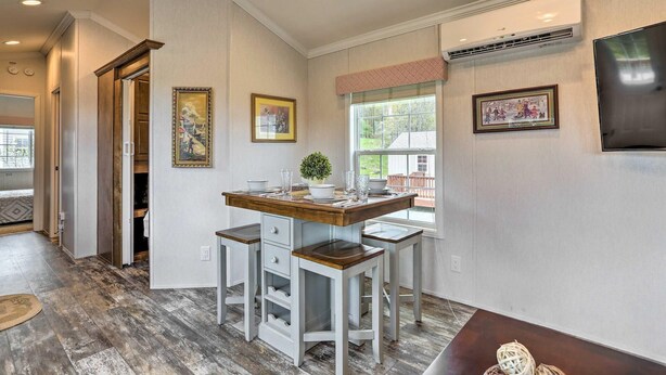 A dining area with a wooden table and white chairs, a small potted plant, and framed artwork on the walls. - Equestrian House- Dosanko Cottage (Pleasant Mount)