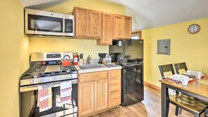 A compact kitchen with a stove, microwave, oven, and refrigerator. Wooden cabinets and a clock on the wall are also visible. - Equestrian House- Estonian Suite (Pleasant Mount)